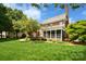Expansive backyard view of a brick home with a screened-in porch, mature trees, and meticulously landscaped garden beds at 5827 Rileys Ridge Rd, Charlotte, NC 28226