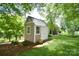 Backyard shed with light tan siding, white trim, a black shingle roof, and a neatly maintained lawn at 5827 Rileys Ridge Rd, Charlotte, NC 28226
