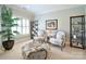 Bright sitting area featuring two armchairs, an ottoman, decorative bookshelves and a large indoor plant at 5827 Rileys Ridge Rd, Charlotte, NC 28226