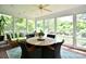 Bright sunroom with dining table, wicker chairs, and a cozy sofa with green cushions overlooking the landscaped outdoors at 5827 Rileys Ridge Rd, Charlotte, NC 28226