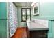 Cozy bathroom featuring mint walls, wooden floors, a shower with curtain, and natural light at 6510 Sharon Hills Rd, Charlotte, NC 28210