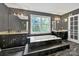 Bathroom featuring a large soaking tub with tiled surround, dual sinks, and a window view of lush greenery at 8524 Quarters Ln, Mint Hill, NC 28227