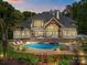 Rear exterior featuring a pool, outdoor kitchen, multiple covered patios, a jacuzzi, meticulous landscaping, and gorgeous architectural details at 10170 Enclave Cir, Concord, NC 28027