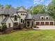 Beautiful home with stone accents, a turret, three-car garage, and lush landscaping at 10170 Enclave Cir, Concord, NC 28027