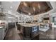 Spacious kitchen with granite island overlooks the living room, featuring stainless appliances and dark wood floors at 10170 Enclave Cir, Concord, NC 28027