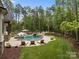 Lush backyard features a beautiful swimming pool with a rock waterfall feature, surrounding landscaping, and ample lounge seating at 10170 Enclave Cir, Concord, NC 28027