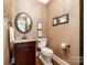 Stylish powder room featuring a vanity with a marble countertop, decorative mirror, and elegant fixtures at 10327 Oak Pond Cir, Charlotte, NC 28277
