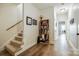 Well-lit hallway with hardwood floors, staircase, and a built-in bookshelf with curated books at 10327 Oak Pond Cir, Charlotte, NC 28277