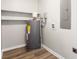 Basement utility room showcasing water heater, electrical panel, white shelving, and gray walls with wood-look flooring at 104 Berry St, Fort Mill, SC 29715