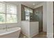 Elegant bathroom featuring a freestanding tub, glass-enclosed shower, and neutral tile flooring at 11000 Strike The Gold Ln, Waxhaw, NC 28173