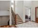 Bright foyer features hardwood floors, stairs with dark metal spindles, and a light gray and white area rug at 11000 Strike The Gold Ln, Waxhaw, NC 28173