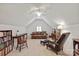 Attic living room with pitched ceiling, ceiling fan, tan carpet and leather furniture, and a bookcase at 11000 Strike The Gold Ln, Waxhaw, NC 28173