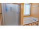 Bathroom featuring a glass door shower and tub with jets near a window with blinds at 12601 Guardhouse Ct, Charlotte, NC 28262
