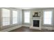Bright living room featuring a classic fireplace, three large windows and hardwood floors at 169 Freeze Nw Ave, Concord, NC 28025