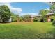 Large grassy backyard with mature trees and brick home at 205 Dogwood Ln, Dallas, NC 28034
