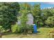 Storage shed in backyard surrounded by mature trees, bushes, and a blue barrel at 205 Dogwood Ln, Dallas, NC 28034
