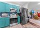 Modern kitchen with stainless steel appliances, teal cabinets, and an open layout to the living area at 222 N Weldon St, Gastonia, NC 28052