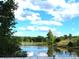 Scenic pond reflecting the sky, framed by lush trees and greenery on a sunny, partly cloudy day at 2530 Sharon Rd, York, SC