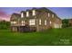 Rear exterior view of brick home highlighting the deck, screened porch, and lush lawn at twilight at 308 Hollister Estates Dr, Waxhaw, NC 28173
