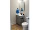 Modern half bath with gray vanity, black hardware, round mirror, and wood-look flooring at 3114 Ansonville Rd, Marshville, NC 28103