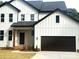 Striking two-story modern farmhouse showcasing white board and batten siding and a dark-brown two-car garage at 3114 Ansonville Rd, Marshville, NC 28103