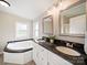 Bright bathroom featuring double sink vanity with black granite countertop and a soaking tub at 317 Berry Trl, Wadesboro, NC 28170