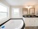 Bright bathroom featuring double sink vanity with black granite countertop and a soaking tub near the window at 317 Berry Trl, Wadesboro, NC 28170