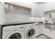 Well-lit laundry room featuring a side-by-side washer and dryer, with gray and white tiled backsplash at 4877 River Hills Dr, Denver, NC 28037