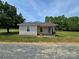 Cozy single-Gathering home exhibits a metal roof, brick chimney and a inviting front porch, all set against a serene backdrop at 5501 Barrier Rd, Concord, NC 28025
