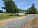 Charming home boasts a durable metal roof, a brick chimney, and a peaceful gravel driveway surrounded by mature trees at 5501 Barrier Rd, Concord, NC 28025