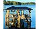 Daytime view of a waterfront dock with boat lift, hanging plants, and outdoor furniture at 578 Stonemarker Rd, Mooresville, NC 28117