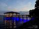 Picturesque waterfront dock featuring a covered boat slip with blue underwater lighting at dusk at 578 Stonemarker Rd, Mooresville, NC 28117