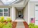 Inviting covered front porch with comfortable seating, an American flag and well-maintained landscaping at 584 Lamorak Pl, Richburg, SC 29729