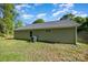 Back exterior view of home with green siding, updated roof, and serene wooded backdrop at 611 Fernwood Dr, Albemarle, NC 28001