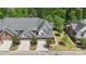 An aerial view of three upscale townhomes with manicured lawns, driveways, and garages, surrounded by mature trees at 907 Ospre Ln, Fort Mill, SC 29708