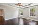 A spacious bedroom featuring a decorative ceiling fan, tray ceiling, and large, bright windows at 907 Ospre Ln, Fort Mill, SC 29708