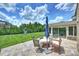 Outdoor patio area with stone flooring, furniture, umbrella, and view of the spacious backyard and sunroom at 9825 Ardrey Woods Dr, Charlotte, NC 28277