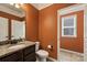 Well-lit bathroom featuring orange walls, a granite countertop, and white fixtures at 9825 Ardrey Woods Dr, Charlotte, NC 28277