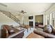 Spacious living room featuring a staircase, fireplace, and comfortable leather furniture at 9825 Ardrey Woods Dr, Charlotte, NC 28277
