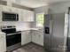 Modern kitchen featuring stainless steel appliances, white cabinets, quartz countertops, and hardwood flooring at 106 E Gibbs St, Dallas, NC 28034