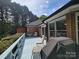 Back deck with light blue floor, partial view of brick, grill, and seating area with foliage in background at 1132 Preakness Nw Ct # 24, Concord, NC 28027