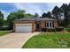 All brick home featuring a two-car garage, well-manicured yard and mature trees at 1132 Preakness Nw Ct # 24, Concord, NC 28027