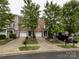 A charming brick townhome with a one-car garage, surrounded by lush landscaping, offering a warm and inviting curb appeal at 1295 Amber Ridge Nw Rd, Concord, NC 28027