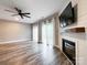 Bright living room with fireplace, ceiling fan, wood-look flooring, and multiple windows with sheer curtains at 1295 Amber Ridge Nw Rd, Concord, NC 28027
