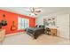 Vibrant bedroom with orange accent wall, ceiling fan, shuttered window and built-in shelving at 134 Lawrence Tee Ln, Mooresville, NC 28117