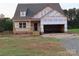 New home features a two-car garage, a covered front porch, and brick foundation detailing at 144 Mason Tanner Ct, Rock Hill, SC 29730