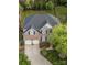 An aerial view showcases a brick home with a pristine roof, two-car garage, and a lush green yard at 15406 Pepperwood Ct, Huntersville, NC 28078