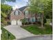 Brick home with two-car garage, lush landscaping, and a blue front door adds curb appeal at 15406 Pepperwood Ct, Huntersville, NC 28078
