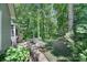 Lush backyard features a stone patio with seating, mature trees and serene landscaping at 160 Fernbrook Dr, Mooresville, NC 28117