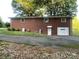 Exterior view of a brick home with a garage and yard featuring mature trees and room to roam at 224 Locust Ave, Locust, NC 28097